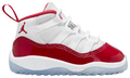 A toddler's Air Jordan 11 Retro Low sneaker in white, red, and navy blue, featuring a glossy red toe cap, red collar lining, and a red Jumpman logo on the side, set against a plain white background.